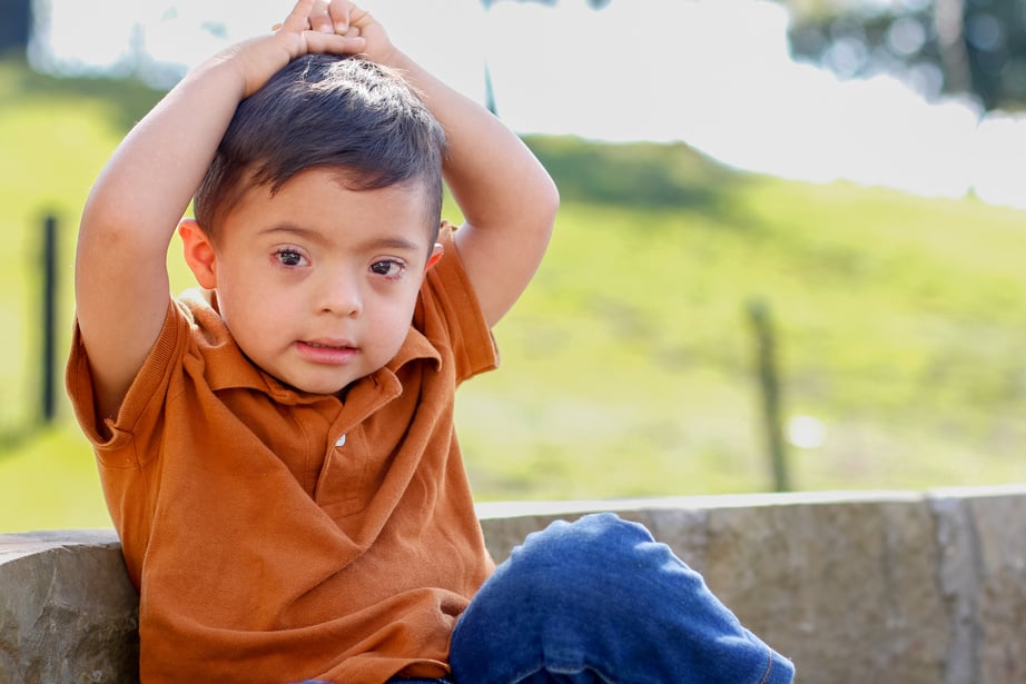 Boy with Down Syndrome Sitting on Stone Bench Surrounded by Nature